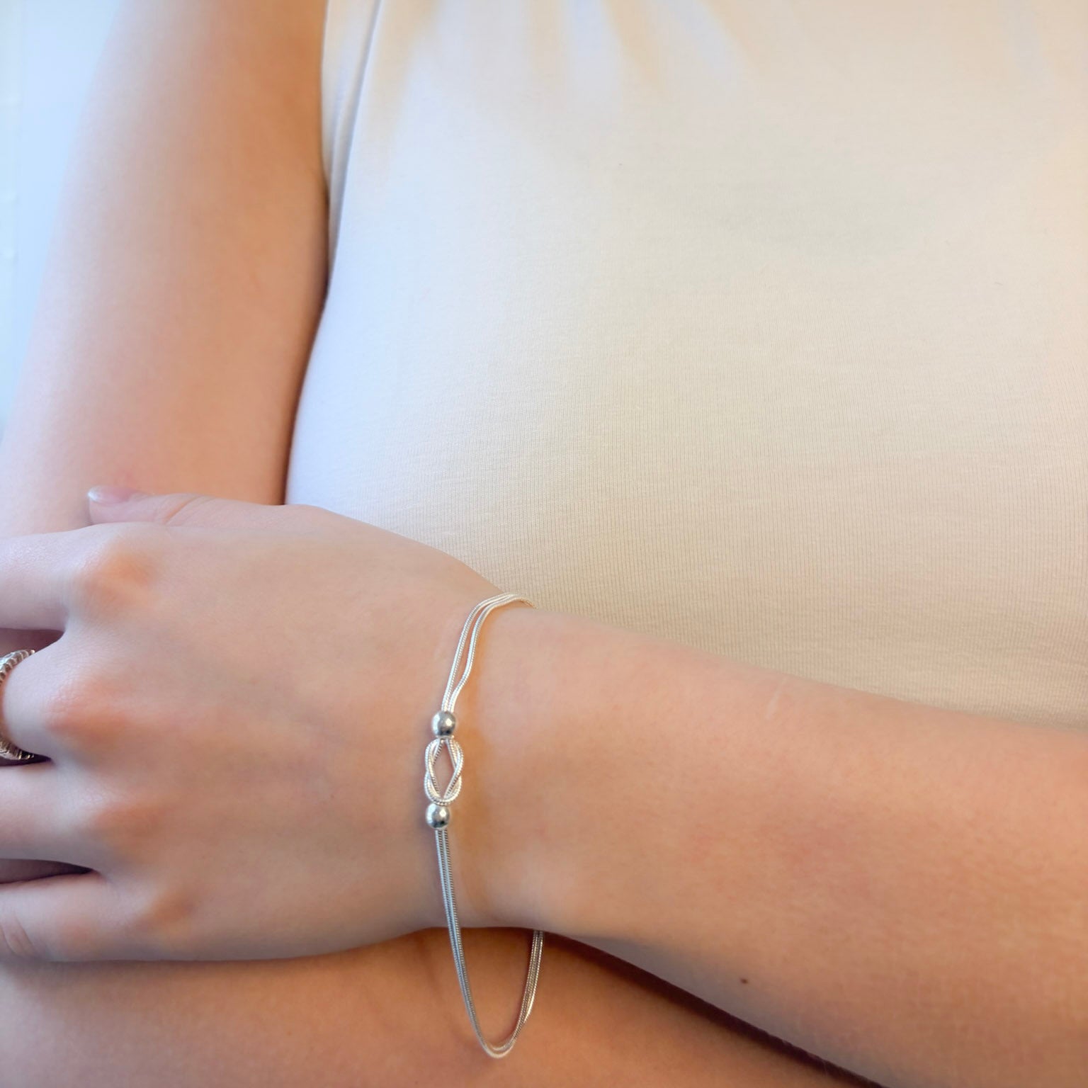 Silver bracelet on a wrist with a plain background