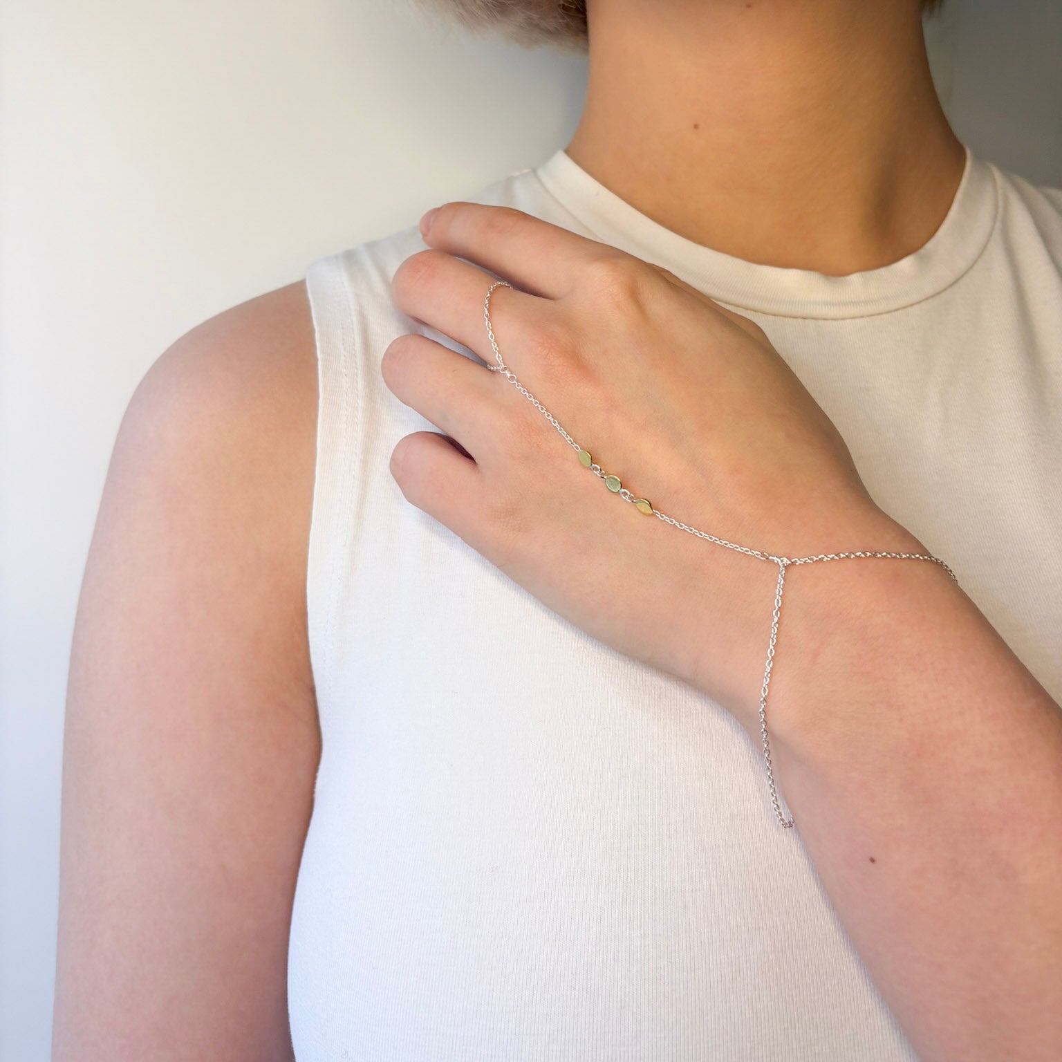 Person wearing a delicate silver bracelet on a plain background