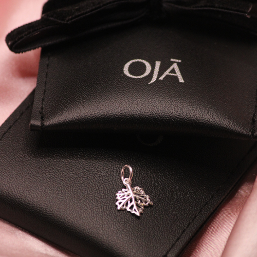 Silver leaf charm on a black OJĀ jewelry pouch