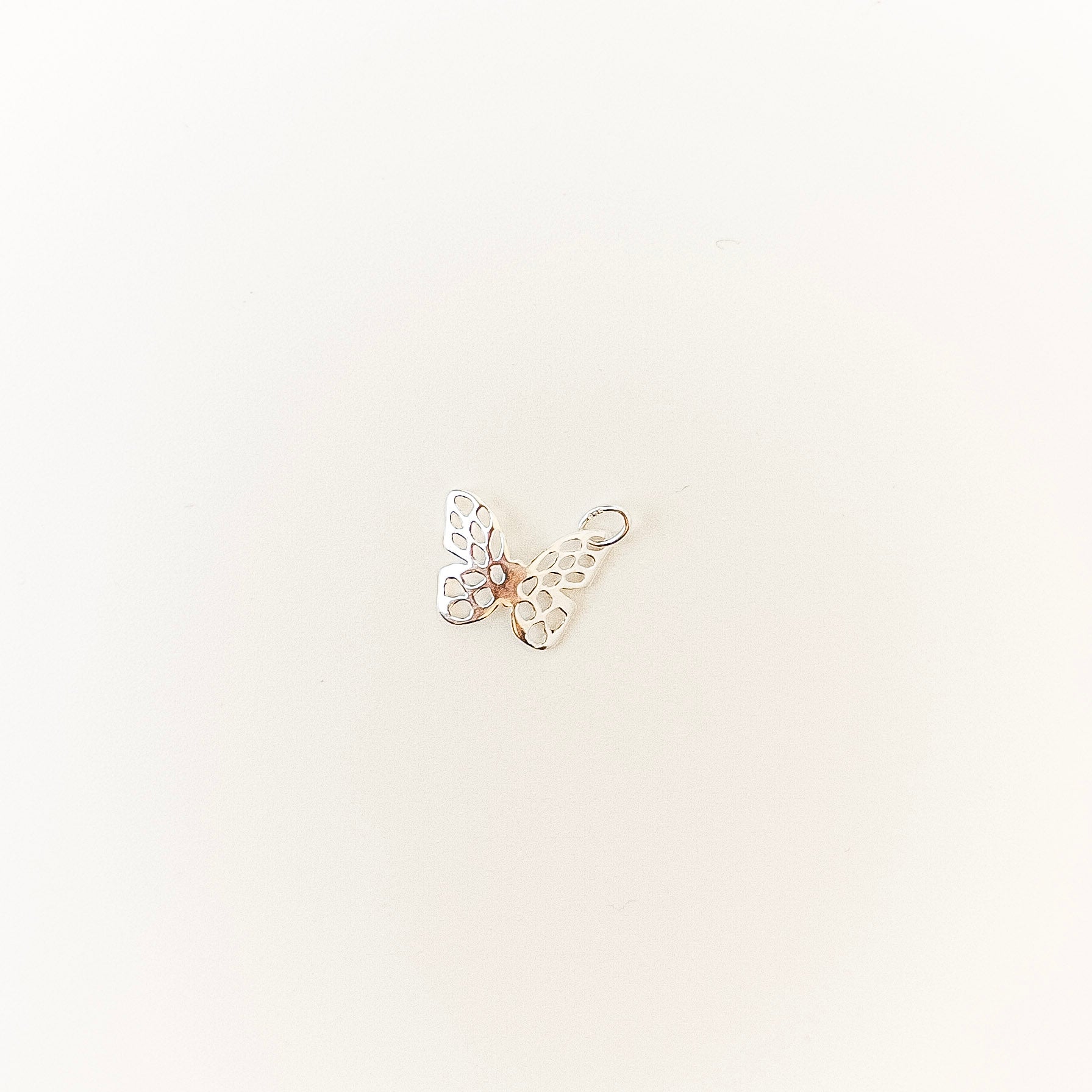 Butterfly-shaped charm on a light beige background