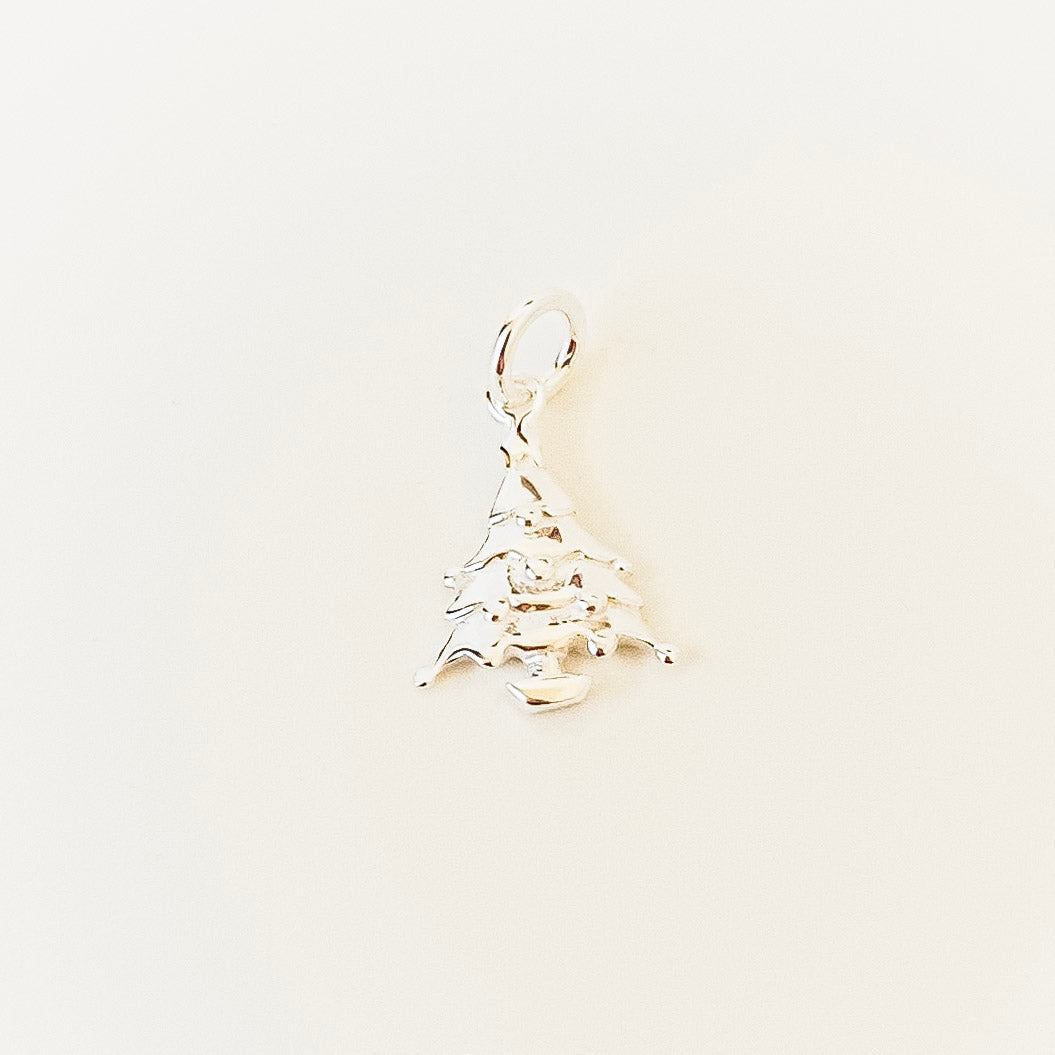 Silver pendant shaped like a mountain on a light beige background