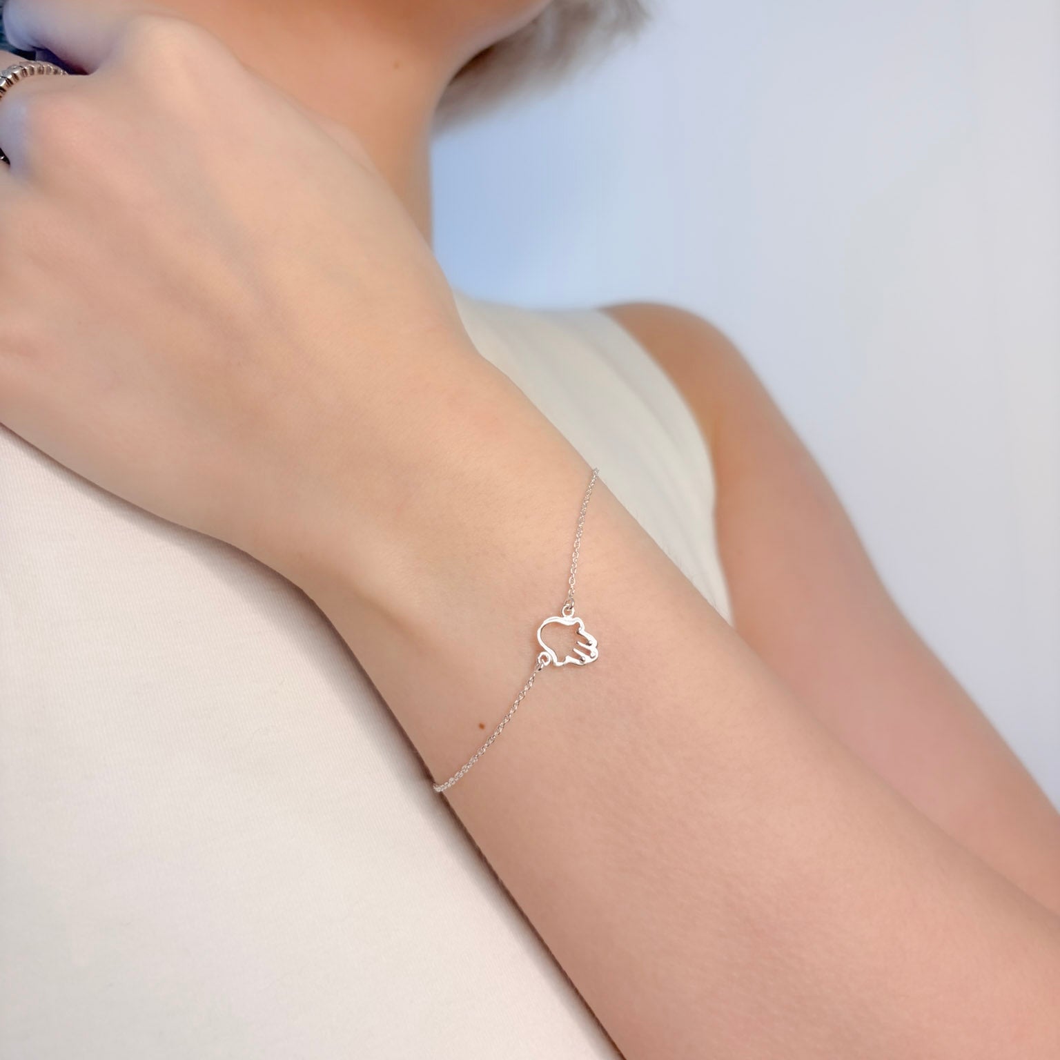 Silver bracelet with a heart design on a person's wrist against a light background
