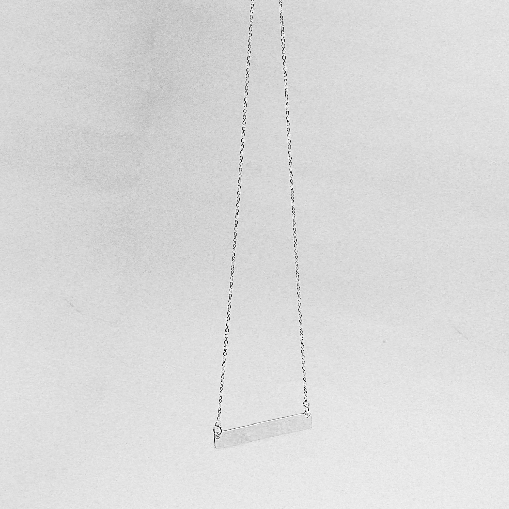 Silver necklace with a bar pendant on a light gray background