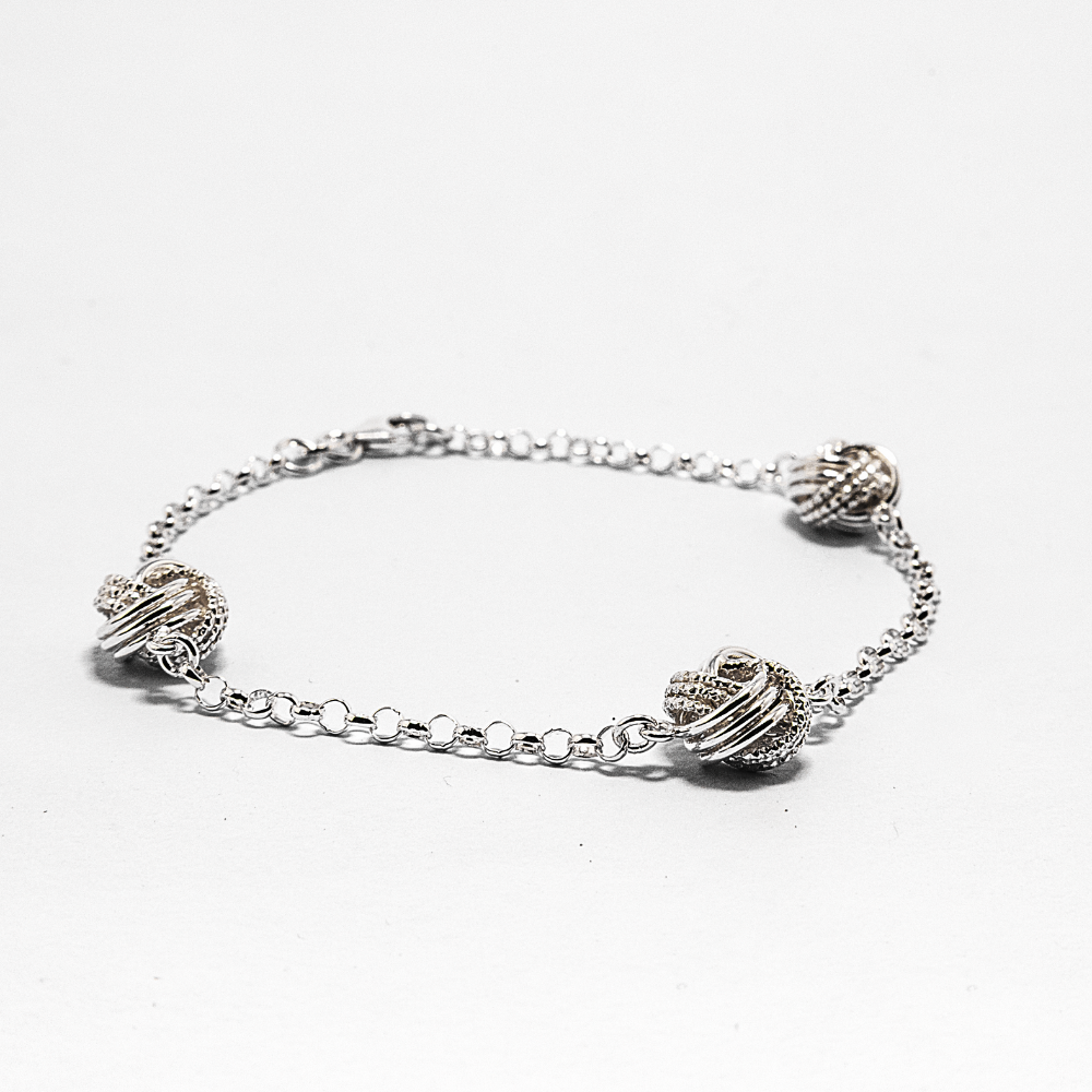 Silver bracelet with three knots on a white background
