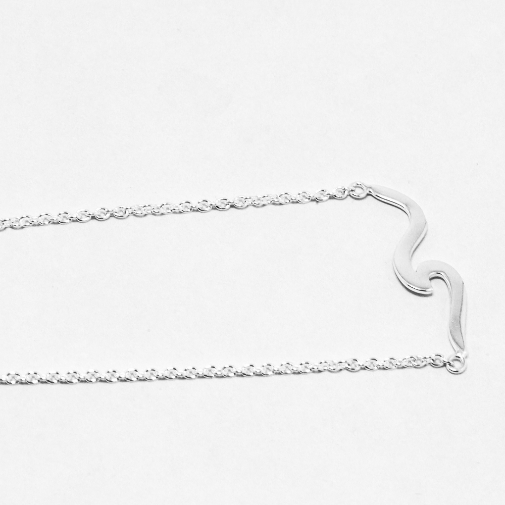 Silver necklace on a light grey background
