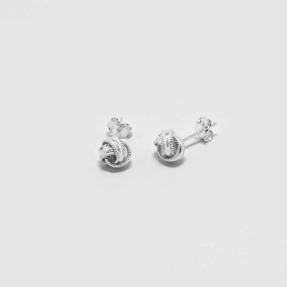 Pair of silver knot earrings on a light gray background