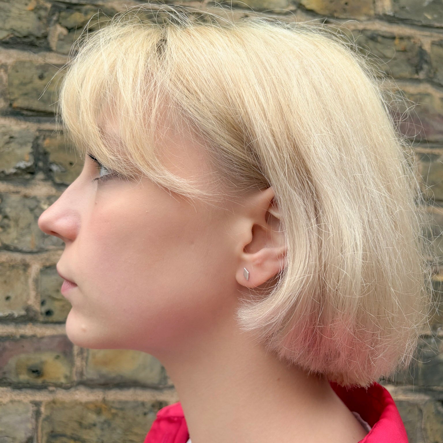 Profile of a person with short blonde hair wearing diamond studs