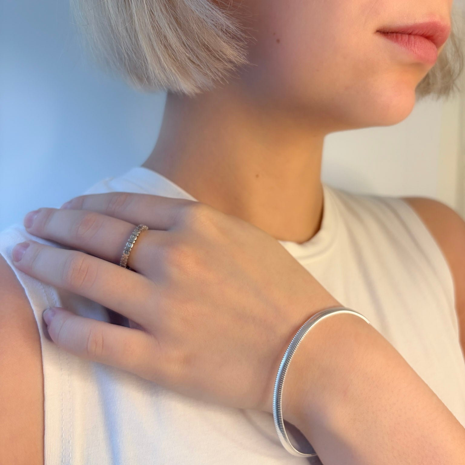 Close-up of a person wearing silver bracelet on a plain background