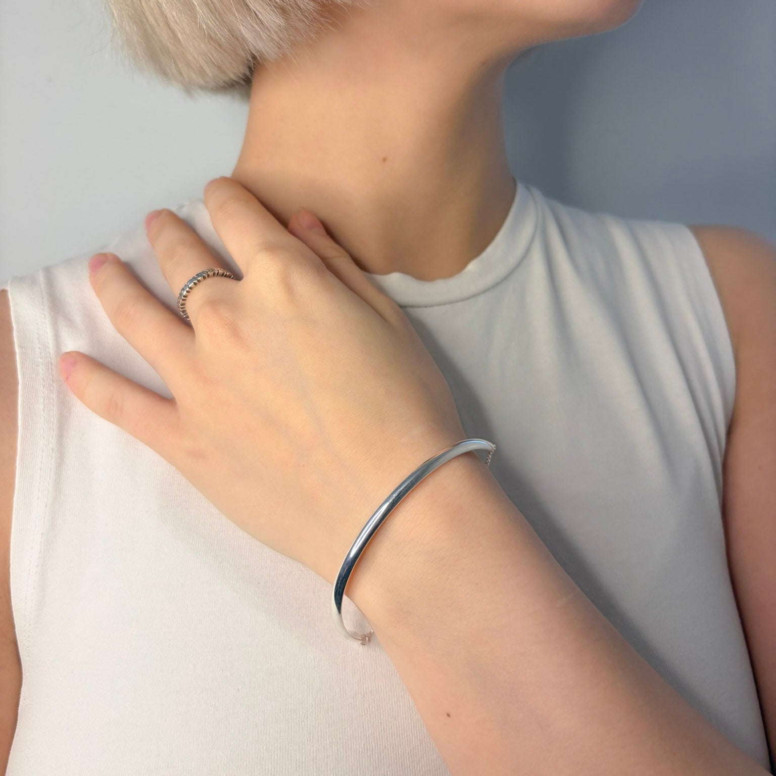 Person wearing a silver bracelet on a plain background