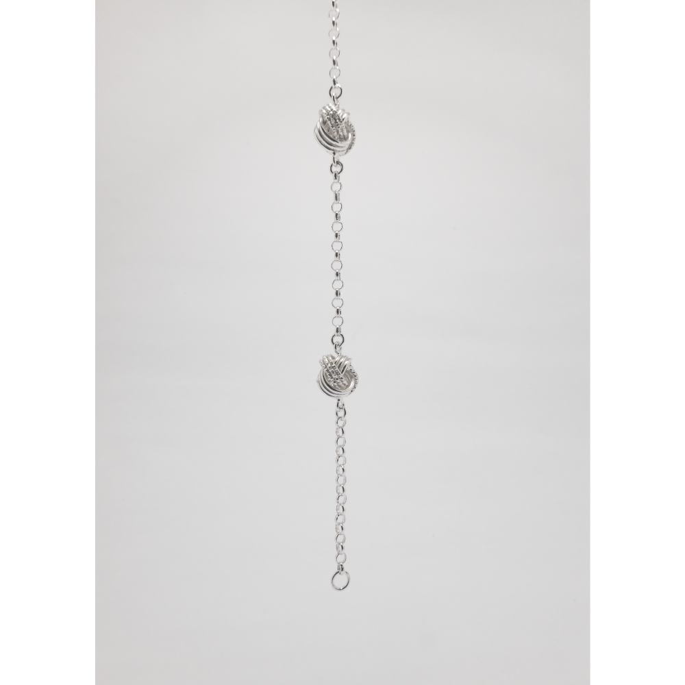 Silver chain necklace with knot pendants on a light grey background