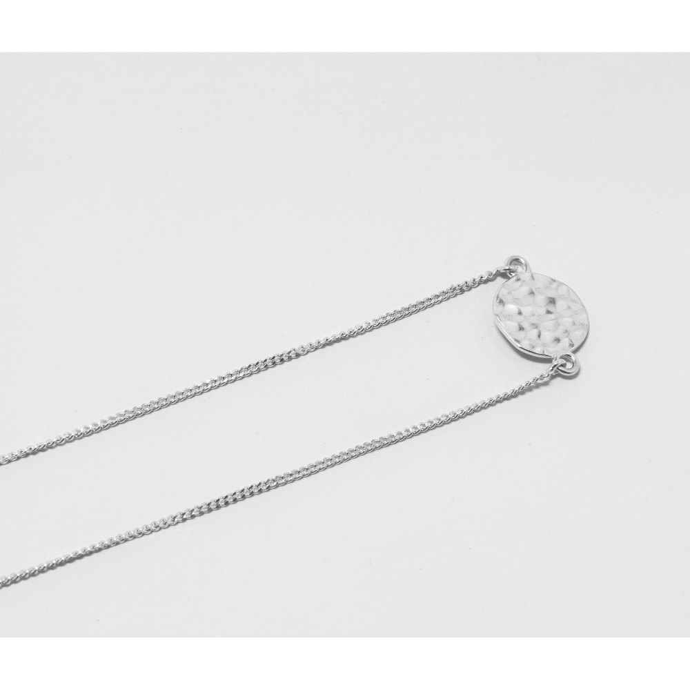 Silver necklace with a Disc-shaped pendant on a light grey background