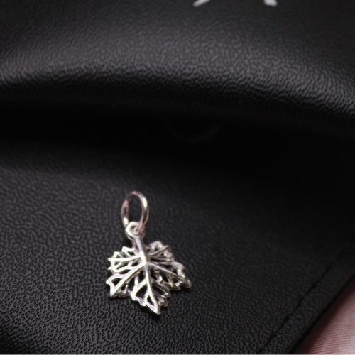 Silver leaf-shaped pendant on a black textured surface