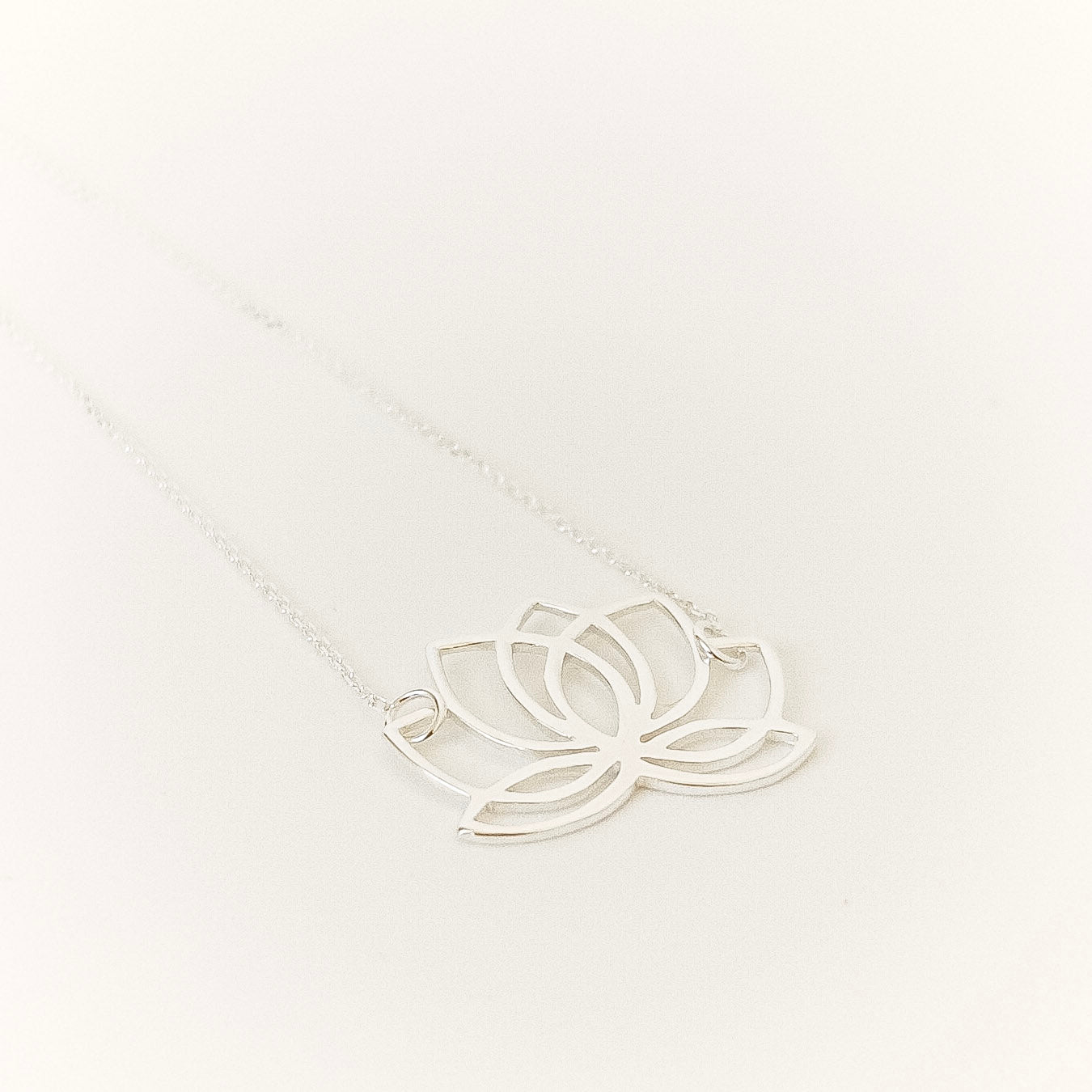 Silver lotus flower necklace on a white background