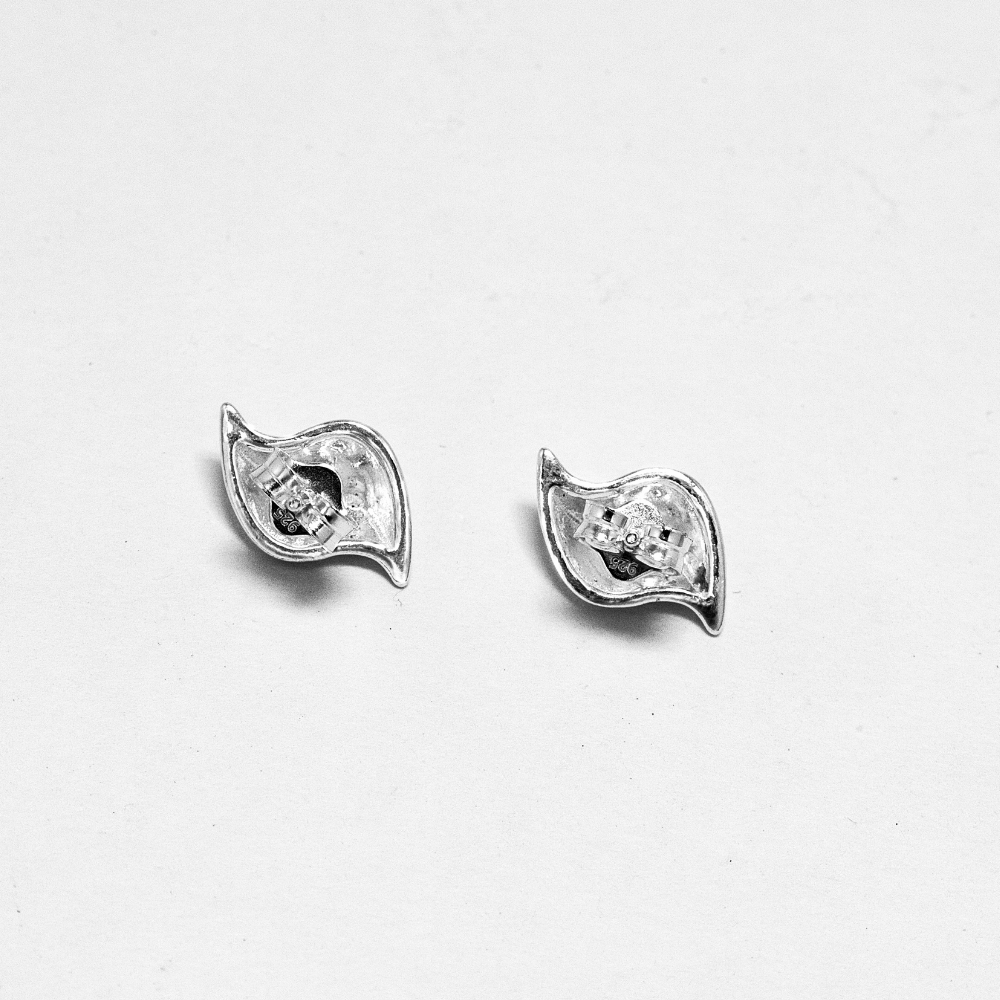 Pair of silver earrings with closure view on a light grey background