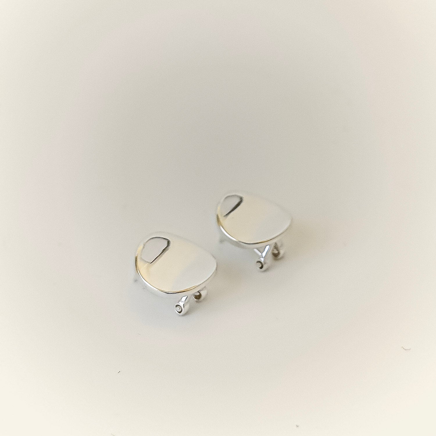 Pair of silver earrings on a light beige background