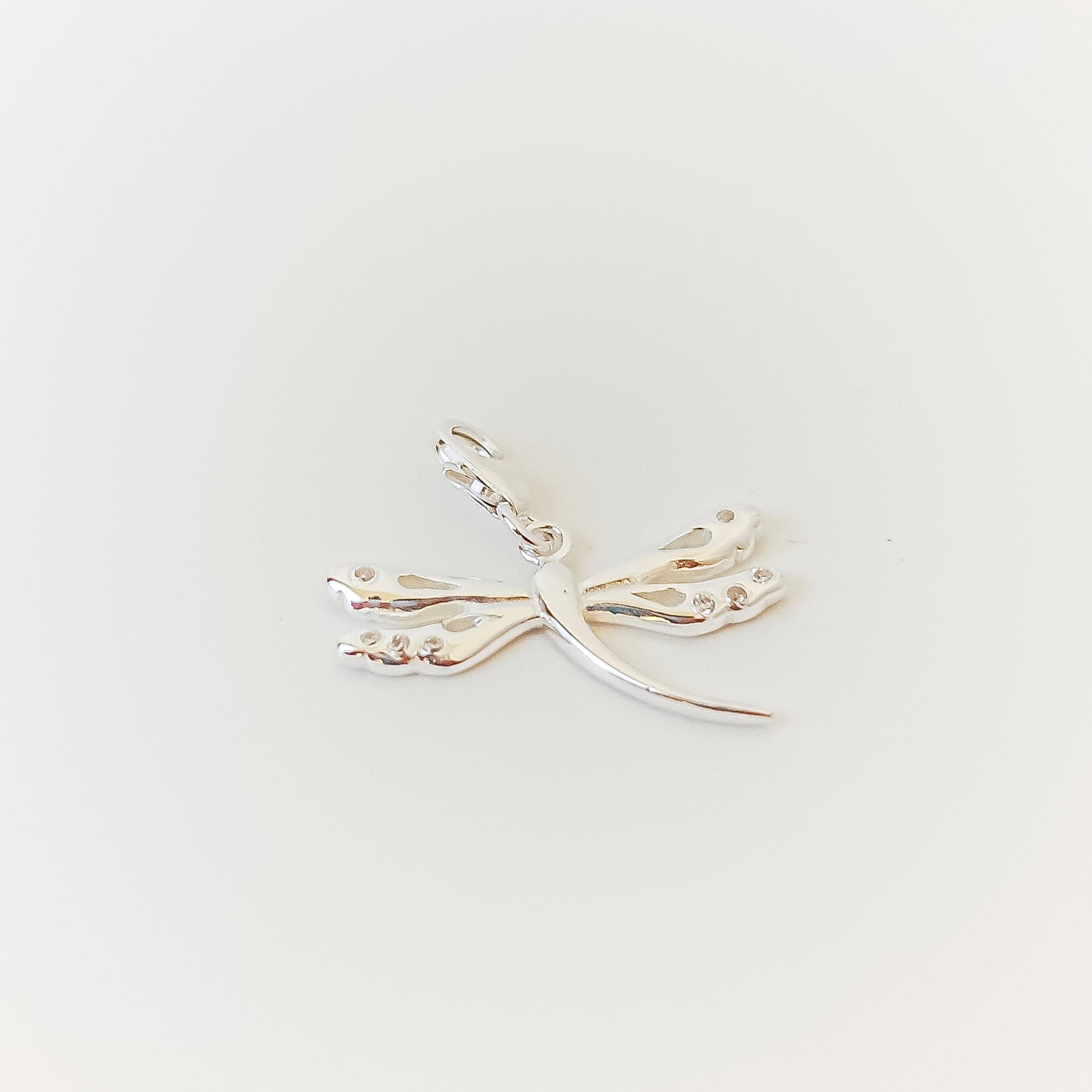 Silver dragonfly necklace on a light gray background