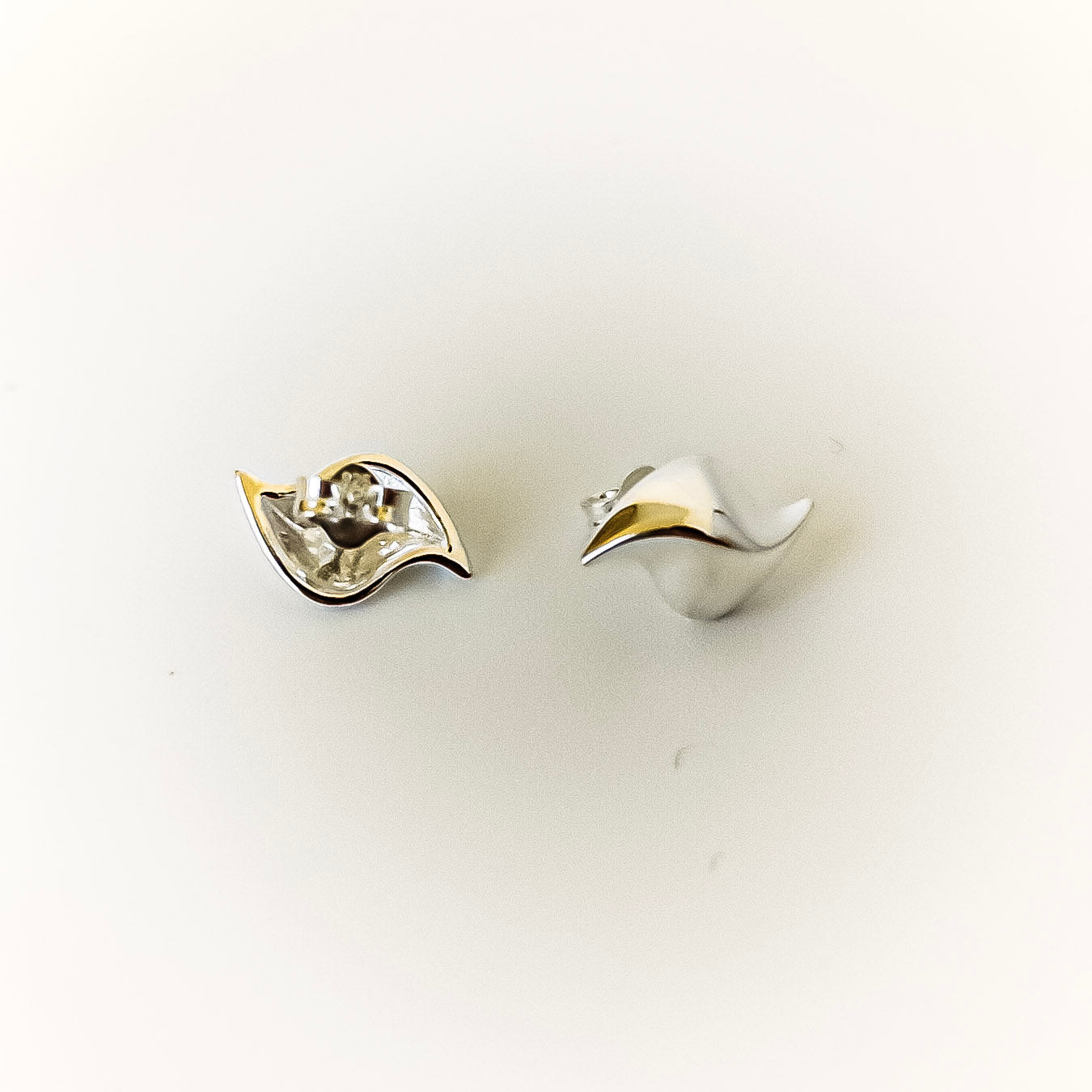 Pair of silver leaf-shaped earrings on a white background