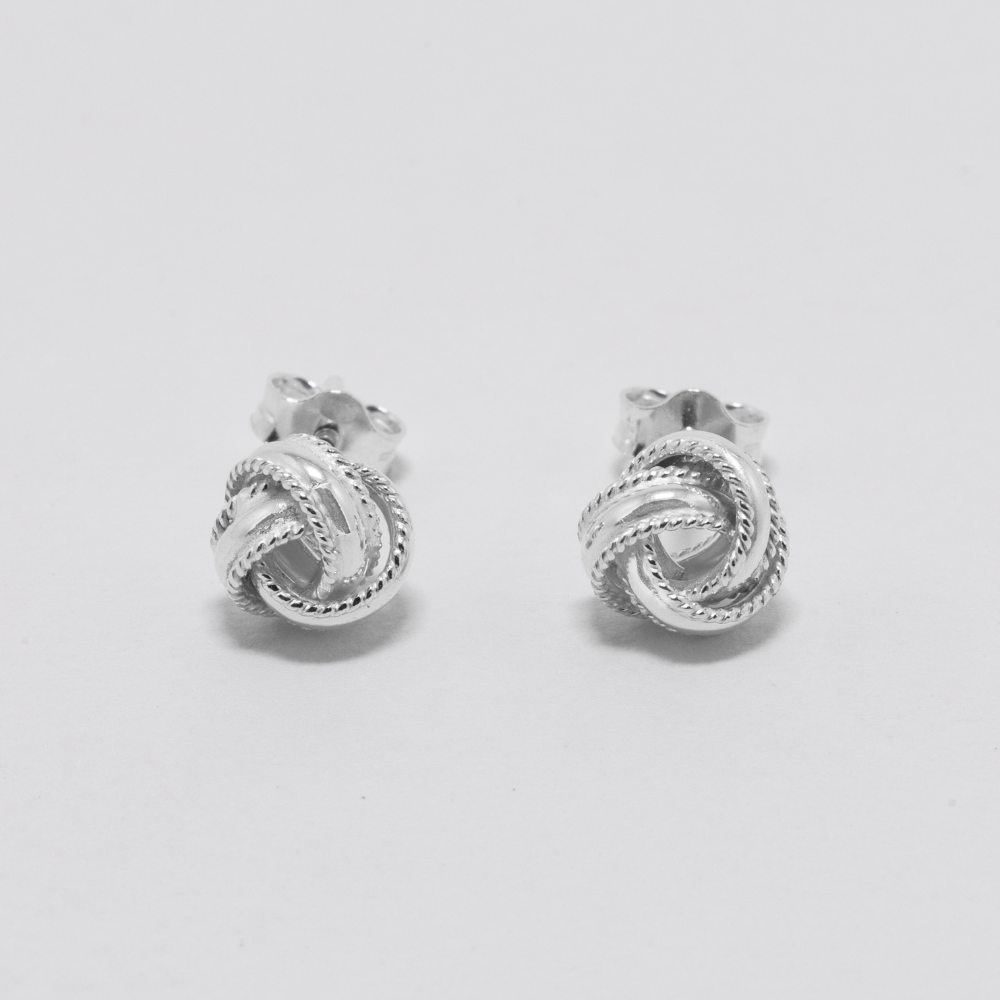 Pair of silver knot earrings on a light gray background