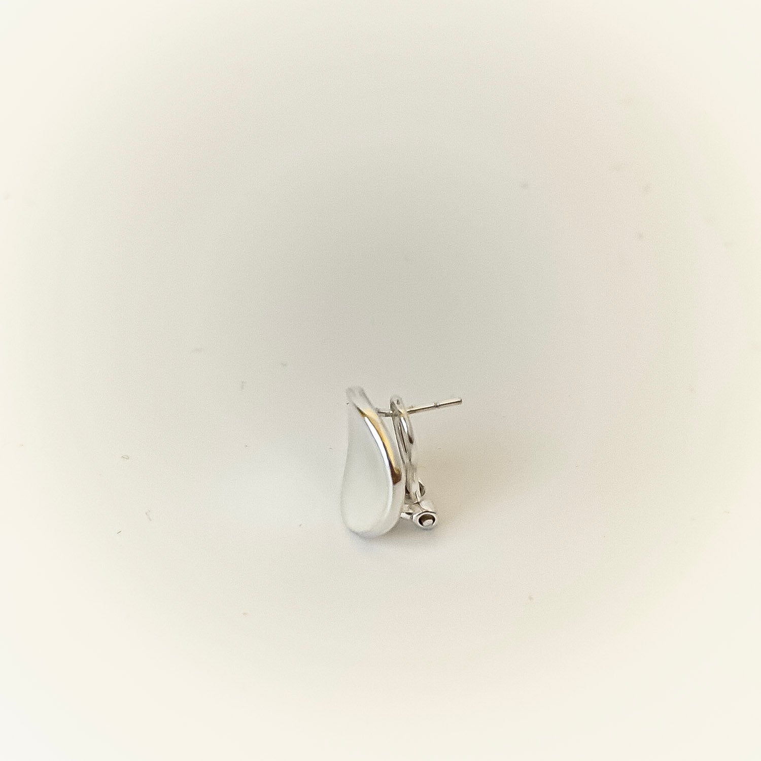 Silver earring on a light gray background