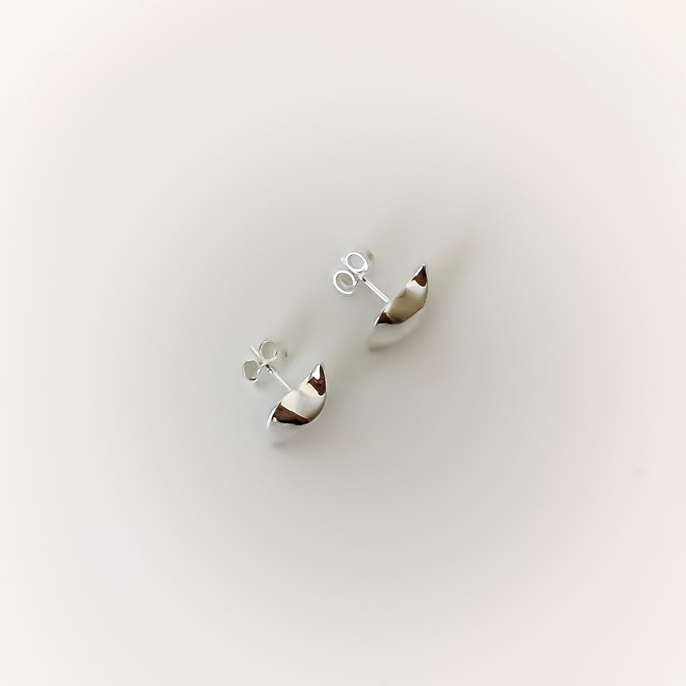 Pair of silver wave-shaped earrings on a light gray background