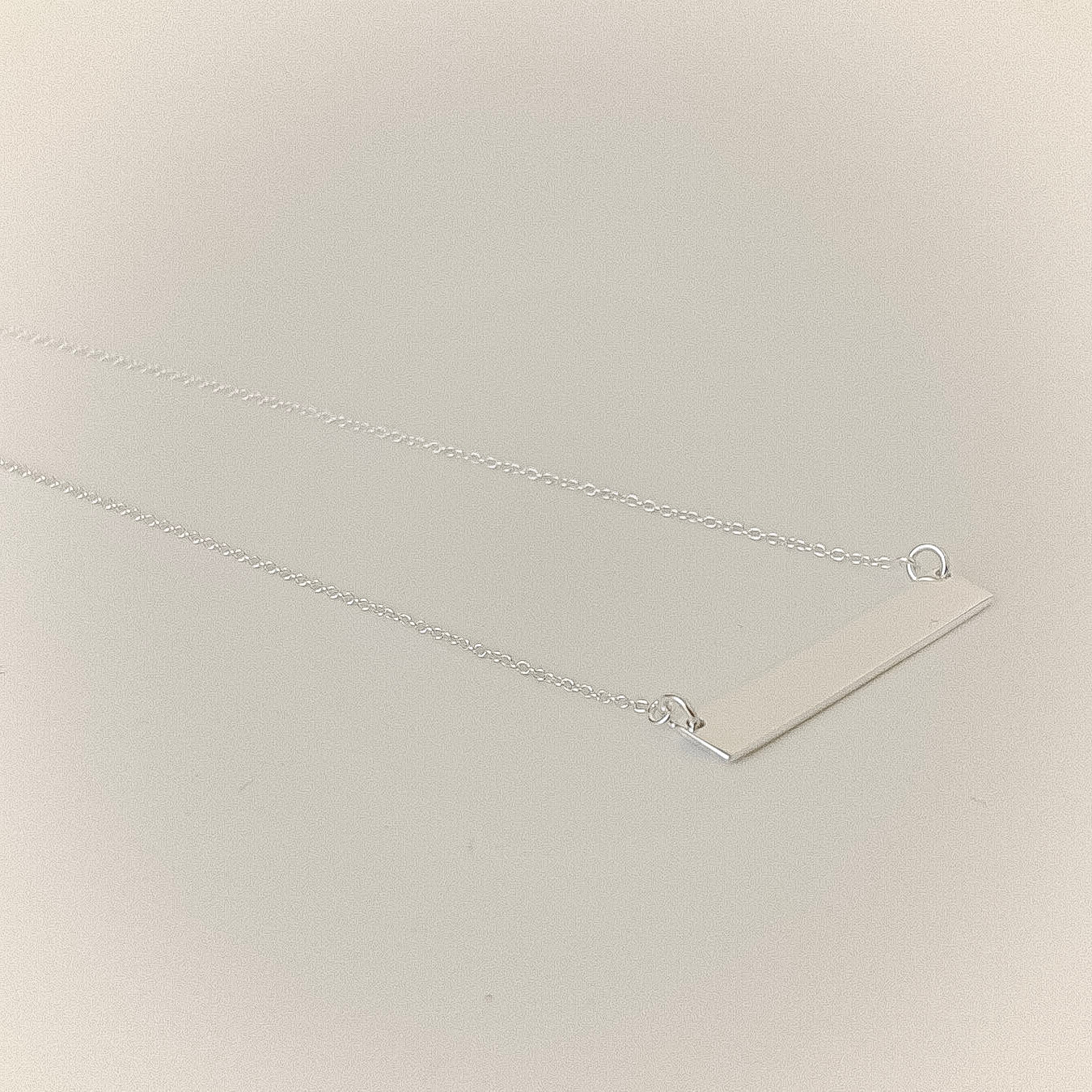 Silver bar necklace on a light bacdrop 