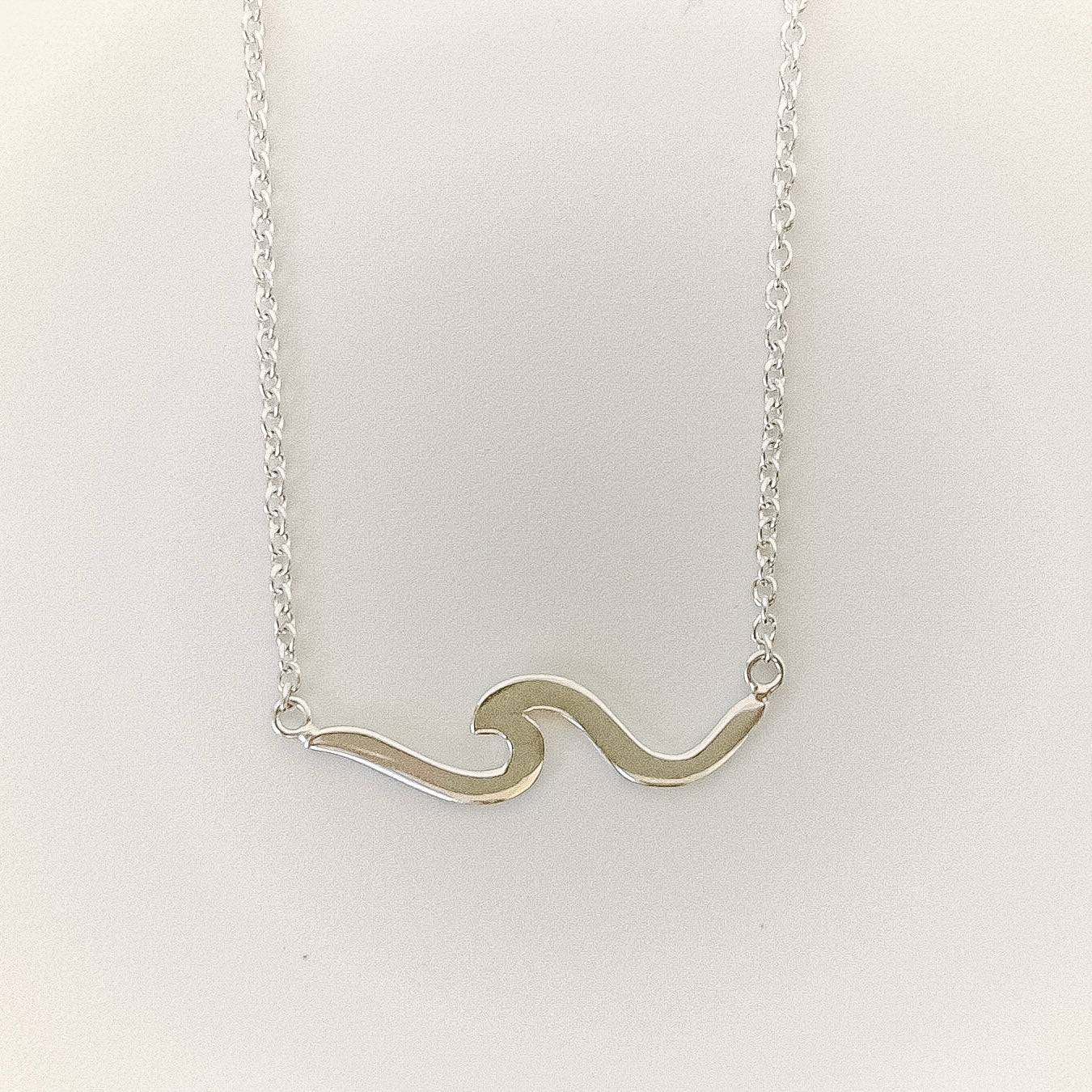 Silver wavy necklace on a light gray background