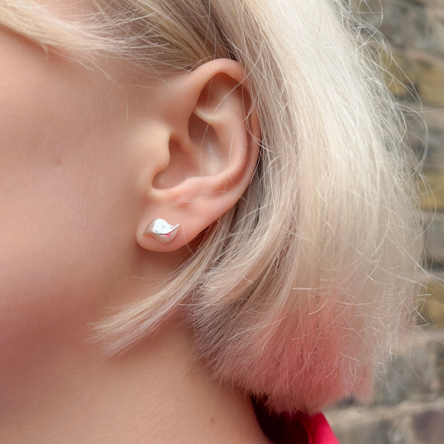 Close-up of an ear with a silver earring, blurred background