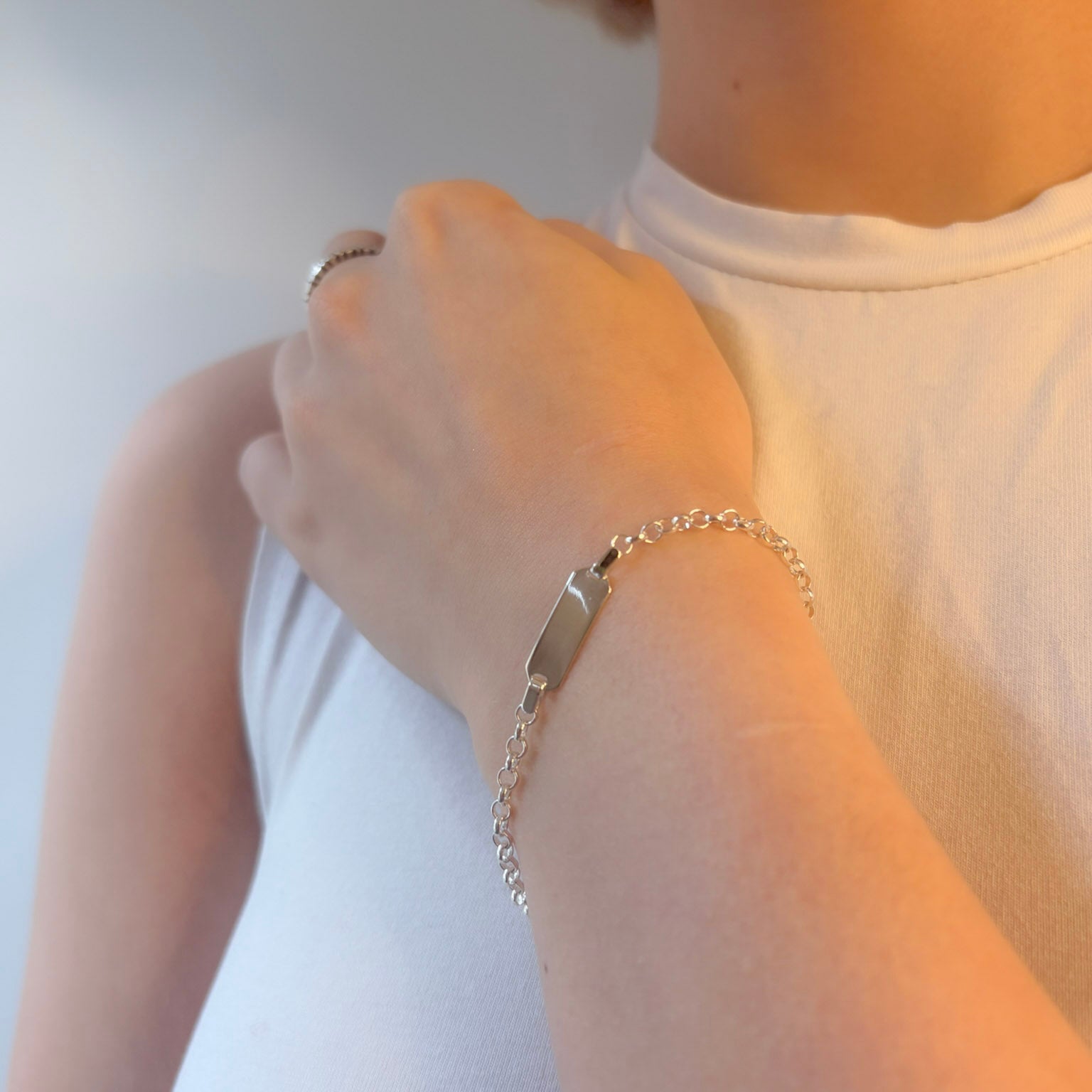 Person wearing a silver bracelet on a plain background
