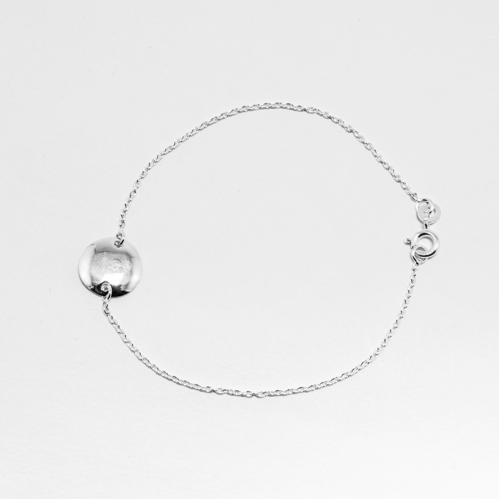 Silver bracelet with halo -shaped charms on a light grey background