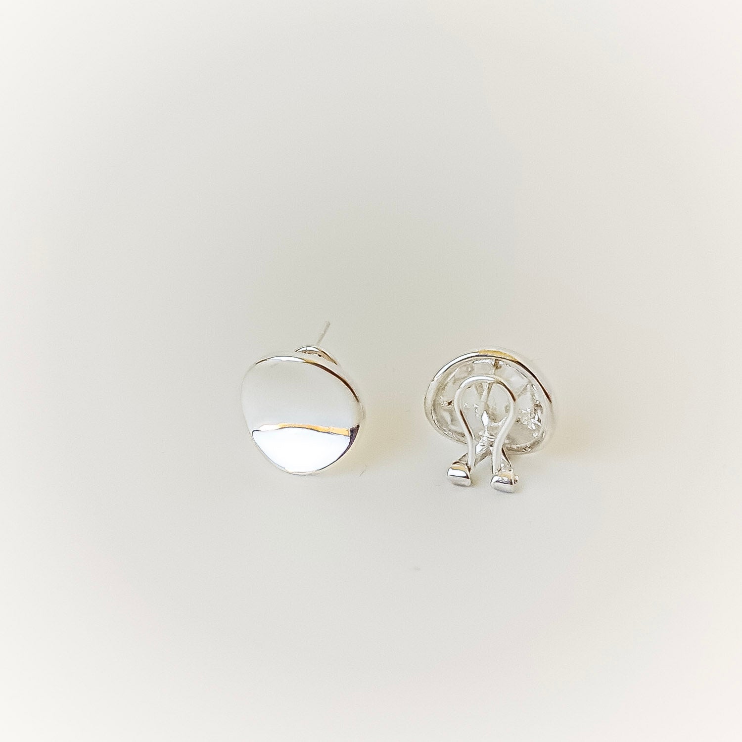 Two silver earrings on a light gray background