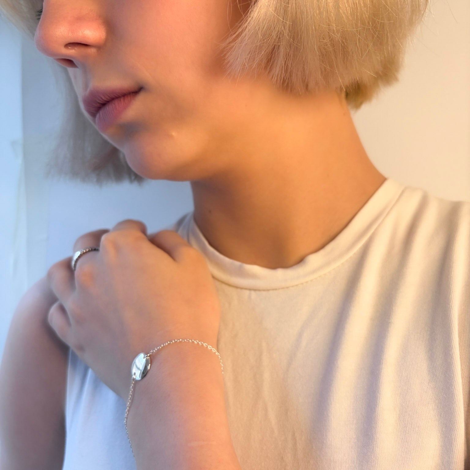 Model wearing a silver bracelet on a plain background