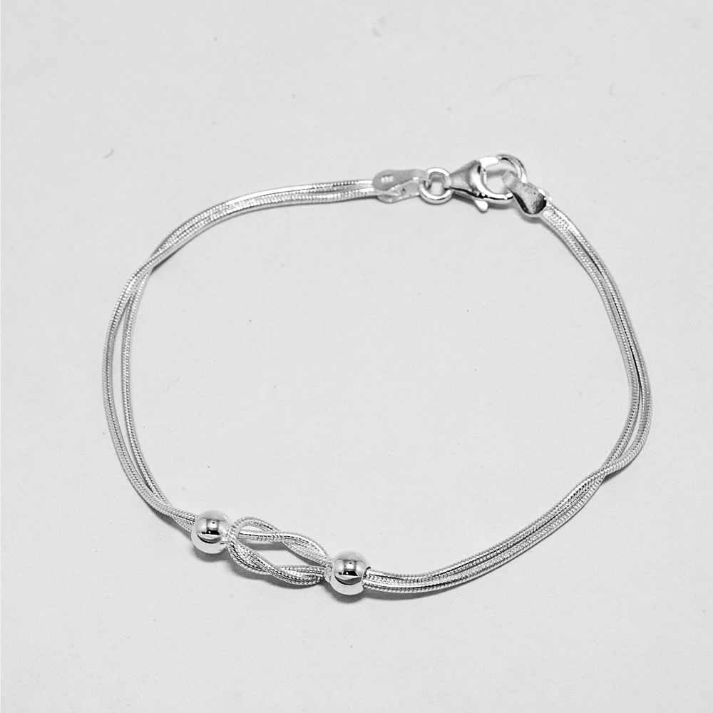 Silver bracelet with a knot design on a light grey background