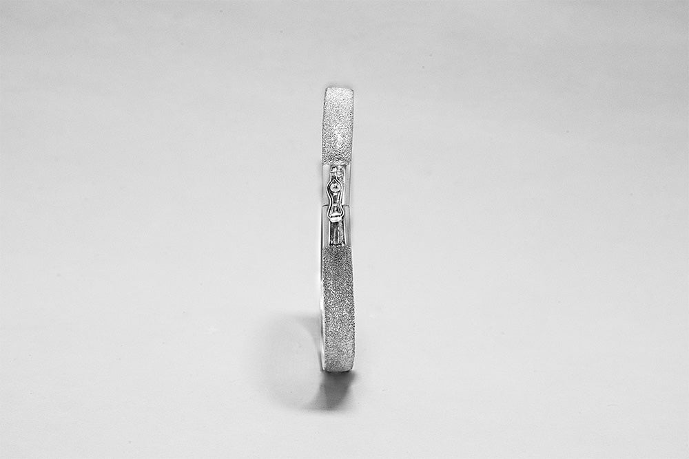 Silver ring with textured band on a light background