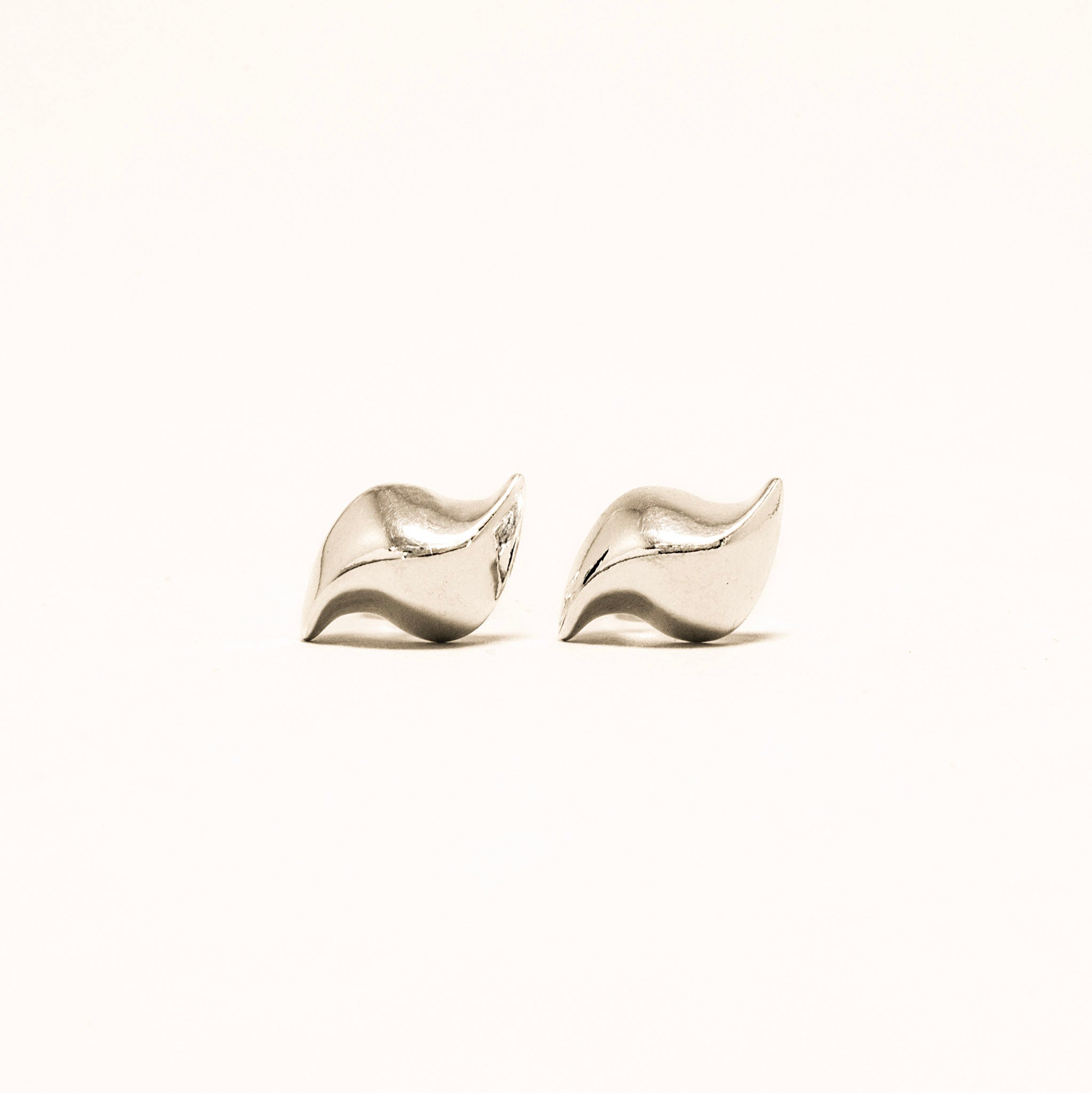 Pair of silver leaf-shaped earrings on a white background
