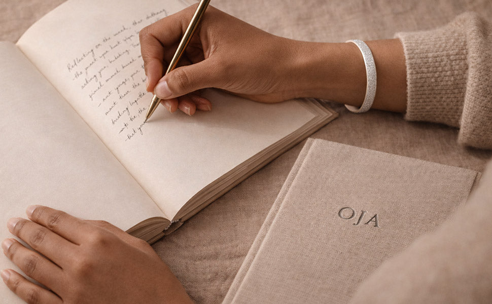 Person writing in a notebook with a gold pen on a textured surface.